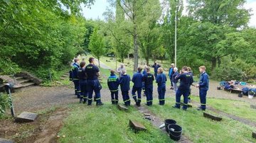 Die Jugendlichen im Gespräch mit dem Zeitzeugen. Im Vordergrund sind die ersten gepflegten Kriegsgräber erkennbar. 
